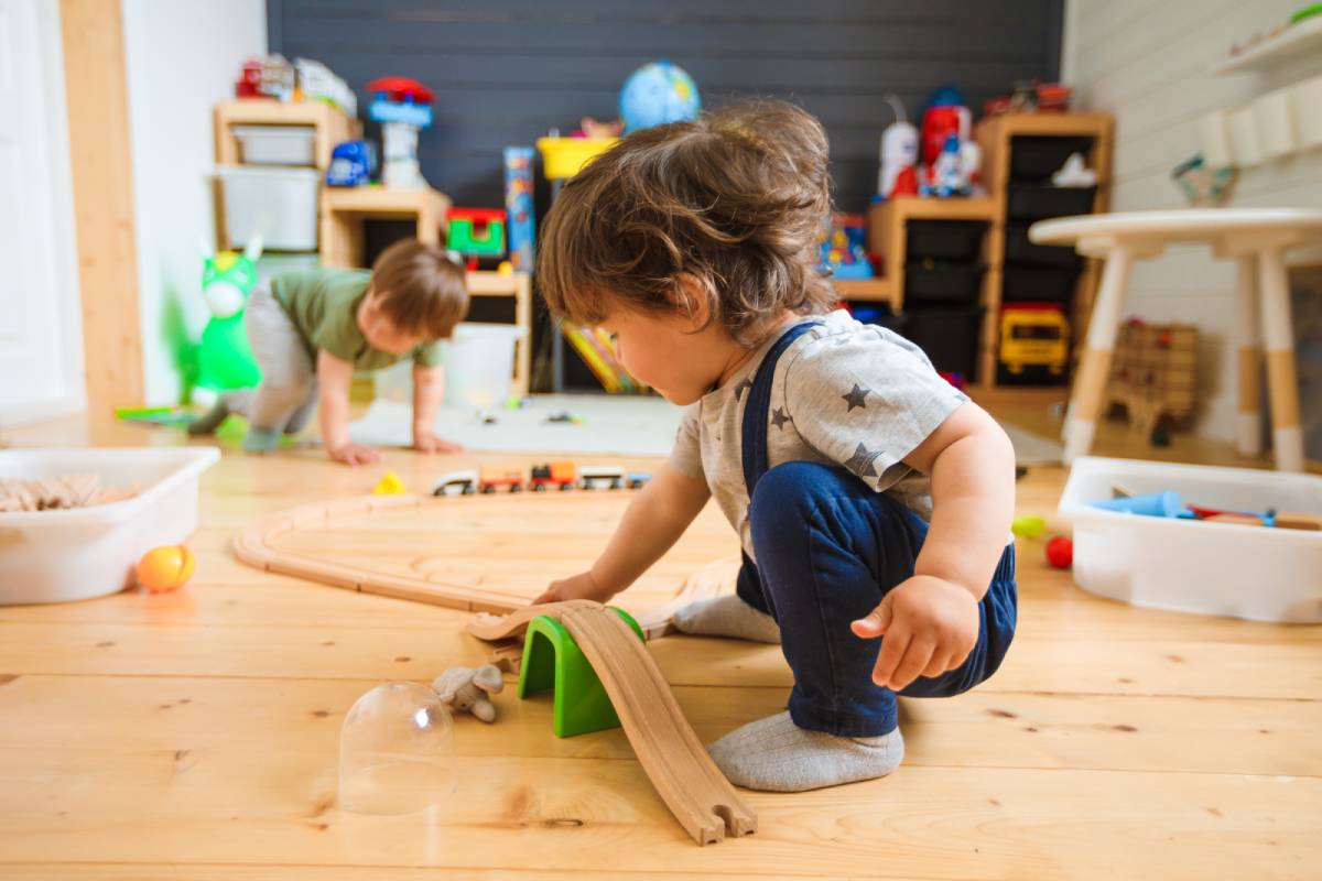 Little boys play with a wooden railroad in an infant daycare.